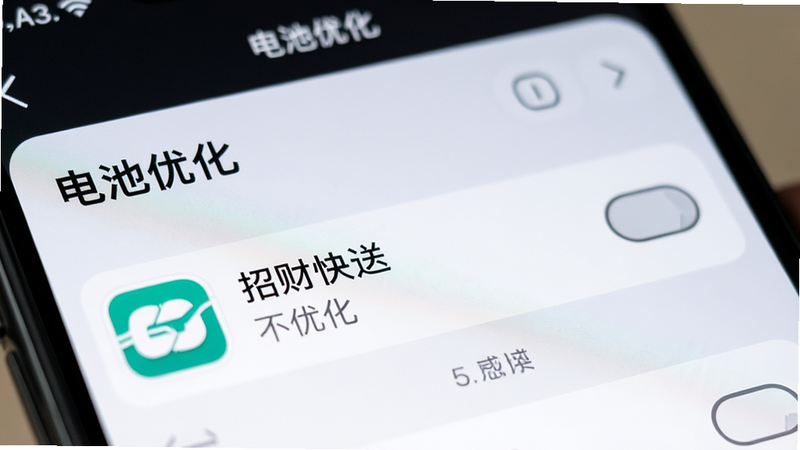 一张手机设置界面的特写照片,显示“电池优化”设置页面,其中“招财快送”应用被标记为“不优化”,背景模糊,焦点清晰在设置项上,风格为真实摄影风,细节锐利,画质高清,干净,无水印,文字“电池优化”清晰可见