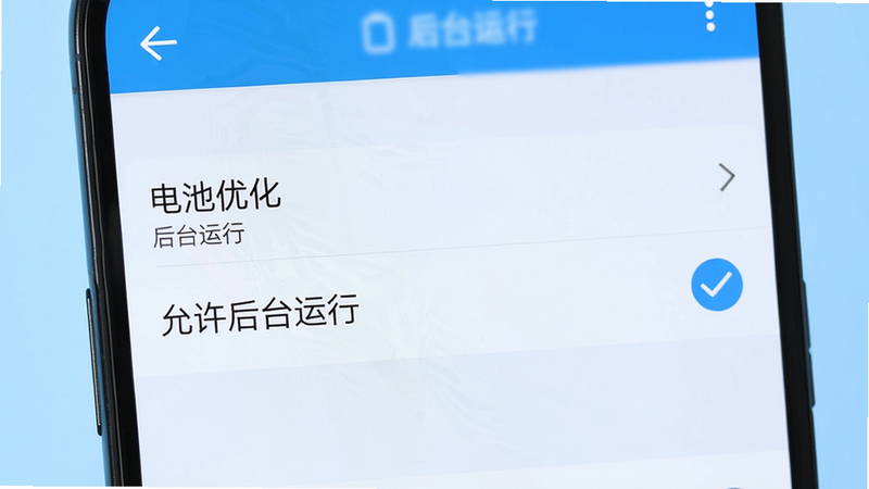 主体为手机设置界面,显示“电池优化”选项,勾选“允许后台运行”,旁边有对勾图标,背景为浅蓝色,风格简洁,高清,无多余元素,文字