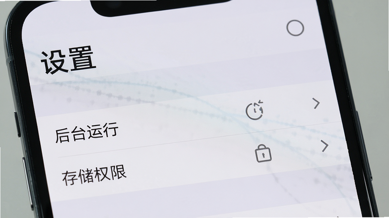 展示手机屏幕上的设置界面,突出“后台运行”和“存储权限”选项,背景为浅灰色,文字“设置”清晰,风格简洁,高清,无多余元素