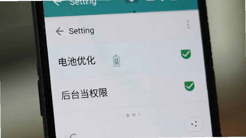 一部安卓手机正在显示设置界面,高亮显示“电池优化”和“后台权限”选项,旁边有简单的勾选标记,背景模糊处理,聚焦于操作界面,风格写实,细节清晰,高清图片,无干扰元素
