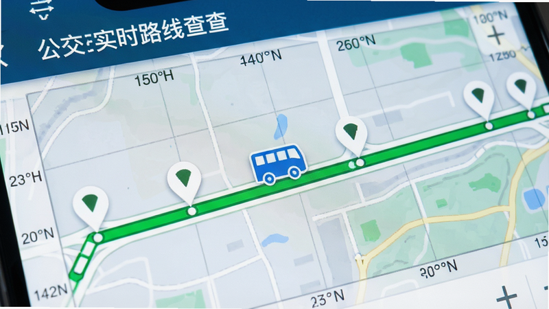 主体为地图界面局部放大图,显示“公交实时路线查”App内的地图模块,布局中心为一条绿色公交线路,沿线分布多个白色站点标记,一个蓝色公交车图标位于线路中段,排版直观,风格科技感,细节包含经纬度网格背景,画质清晰,干净,无多余元素