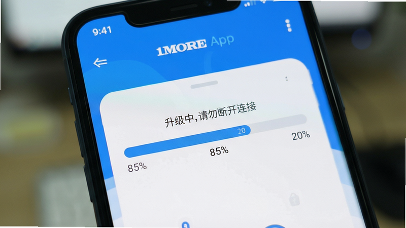 手机屏幕上显示1MORE App的固件升级进度条,背景模糊处理,突出屏幕内容。进度条显示为85%,上方有“升级中,请勿断开连接”字样。风格为扁平化设计,色彩以蓝白为主,体现科技感与安全性。画质清晰,无杂乱背景,聚焦于核心操作界面。