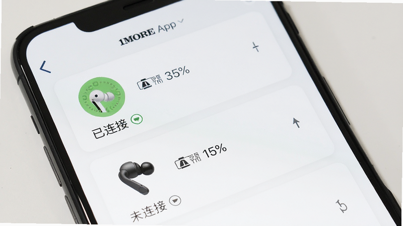 手机屏幕显示1MORE App的设备列表页面,列出两只不同型号的耳机图标,分别显示“已连接”和“未连接”状态。界面布局整齐,图标清晰。背景为纯白色,突出界面内容。风格为简约商务风,细节处有电量百分比显示。画质清晰,无阴影干扰,直观展示多设备管理功能。