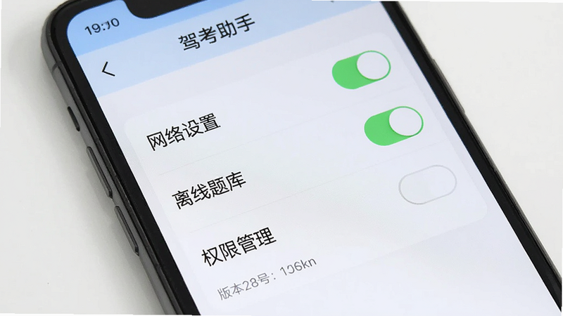 主体为手机屏幕显示“驾考助手”设置页面,布局包含“网络设置”、“离线题库”、“权限管理”选项,风格简洁,细节展示开关按钮和版本号信息,画质清晰,干净,无多余元素