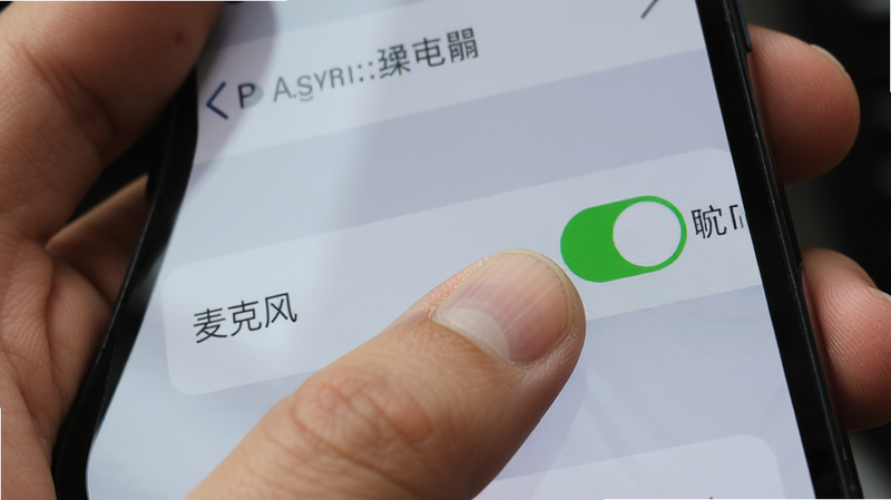 主体为一只手握持智能手机,屏幕上显示设置菜单,手指正在点击