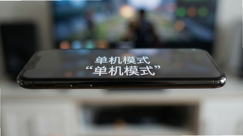 主体为手机侧面特写,屏幕亮起显示游戏主菜单,背景模糊处理突出手机,布局简洁,排版居中,风格为写实摄影风,细节展示屏幕反光,画质高,干净,无多余元素,文字加引号“单机模式”