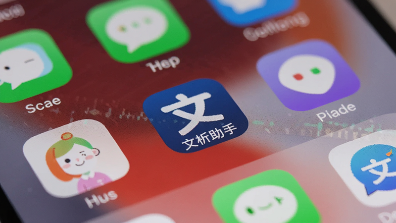 手机桌面特写,显示“文析助手”图标,周围有其他常用应用图标,背景为壁纸,光线柔和,高清