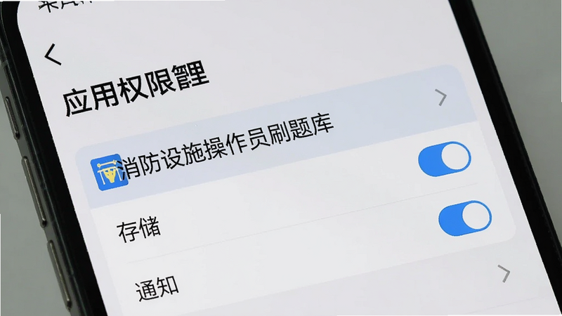 生成一张手机设置界面的特写图,显示“应用权限管理”页面,高亮选中“消防设施操作员刷题库”,下方勾选了“存储”和“通知”权限,背景为浅灰色,界面简洁明了,体现安全与隐私保护,画质清晰,无水印