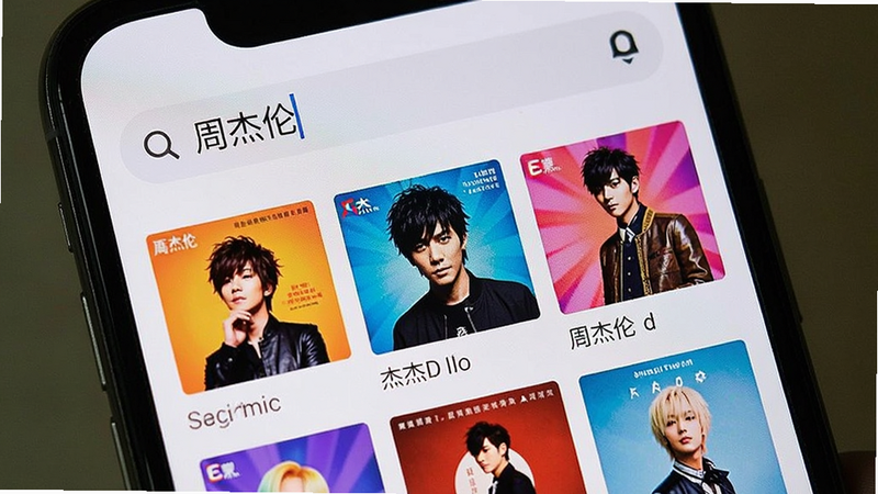 手机界面展示音乐搜索页面,顶部搜索框内输入“周杰伦”,下方列出多张专辑封面,色彩鲜艳,布局紧凑,体现海量曲库的丰富性