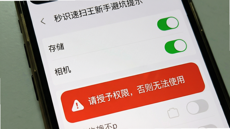 主体:秒识速扫王新手避坑提示截图;布局:手机屏幕上显示一个设置页面,权限管理列表中的“存储”和“相机”右侧有绿色开启图标;下方有一个红色警告弹窗:“请授予权限,否则无法使用”;排版:UI简洁,背景白色;风格:真实截图风格,带手机边框;细节:警告弹窗带感叹号图标,权限列表有开关;画质:高清且干净。