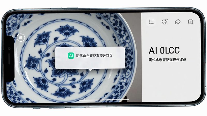 主体为手机拍摄一件青花瓷盘,屏幕显示AI识别结果弹窗,标注“明代永乐青花缠枝莲纹盘”;布局为手机横向拍摄特写,排版左侧实物右侧识别信息;风格为科技感UI叠加真实瓷器;细节包括盘心图案、弹窗阴影;画质细腻干净,无多余元素