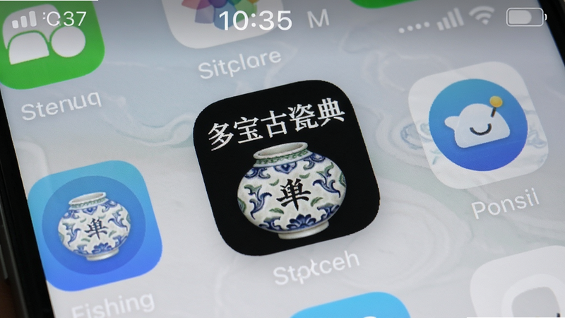 主体为手机屏幕上显示“多宝古瓷宝典”APP安装完成界面,桌面图标带有陶瓷纹理标识;布局为手机桌面截图,周围有少量常用应用图标;排版自然;风格真实手机截屏;细节包括图标阴影、状态栏时间;画质清晰干净,无多余文字