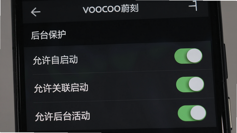 一张手机截屏展示VOOCOO蔚刻设置界面中的“后台保护”选项,顶部有“VOOCOO蔚刻”字样,列表中显示“允许自启动”“允许关联启动”“允许后台活动”,三个开关全部开启,背景暗色,风格系统级UI,细节清晰,画质高清。