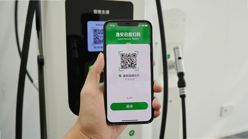 一个用户手持手机扫描充电桩二维码的实拍场景,手机屏幕显示逸安启超充扫码界面,背景为直流快充桩,布局以手机为中心,风格真实生活化,细节包括二维码识别成功提示、充电启动按钮绿色,画质清晰,背景干净