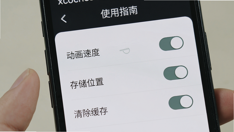 主体是手机屏幕上显示xzochess设置界面,布局列表式,包含“动画速度”、“存储位置”、“清除缓存”等选项。风格清爽,细节包括每个选项右侧的开关按钮,画质干净,文字“使用指南”出现在顶部。