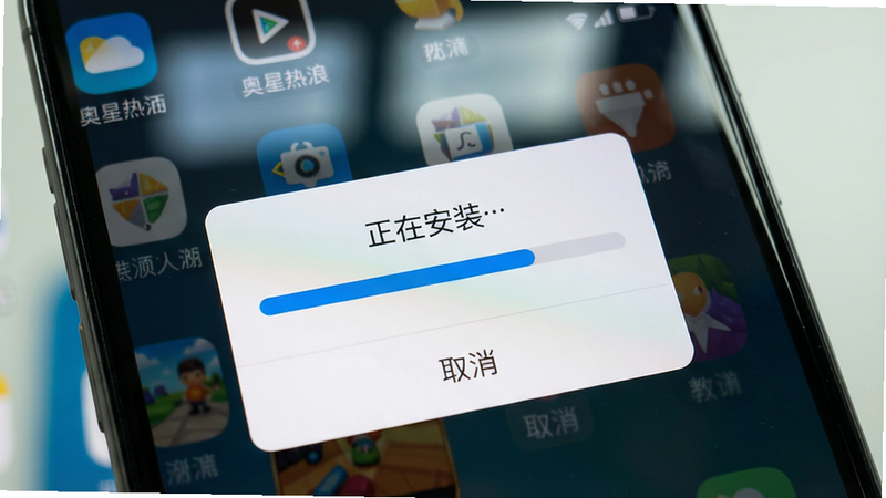 主体:手机屏幕上显示奥星热浪游戏安装过程,正在安装进度条到一半,背景是桌面图标。布局:手机屏幕特写,安装提示框居中,进度条蓝色。排版:文字“正在安装…”,下方有“取消”按钮。风格:真实手机截图风格,细节:屏幕反光,右上角电量图标。画质:高清,干净无多余文字。
