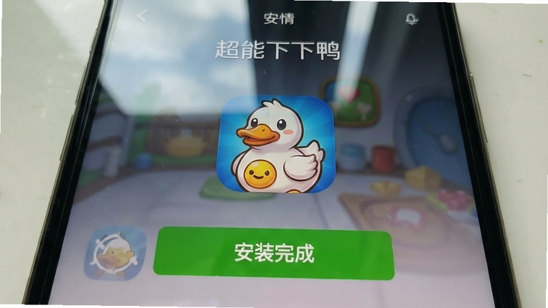 主体:超能下蛋鸭手机安装界面截图,显示“安装完成”按钮和游戏图标;布局:居中;排版:UI界面;风格:真实手机截图风格;细节:屏幕反光效果,图标为鸭子;画质:清晰真实,无多余元素
