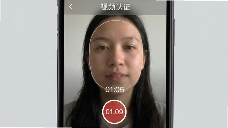 主体:手机屏幕展示奔现的视频认证界面,一个用户正在录制自我介绍视频,画面中显示面部轮廓。布局:手机竖屏显示,顶部有“视频认证”标题,下方有录制按钮和倒计时。排版:界面简洁,功能按钮集中在下半部分。风格:真实 photograph 风格但带一点磨皮效果,突出人物自然表情。细节:录制按钮为红色圆形,倒计时数字清晰,背景是纯色浅灰。画质:高清视频截图效果,人物皮肤纹理清晰,光线柔和。
