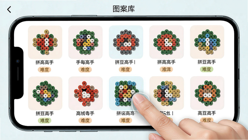 拼豆高高手手图案库界面,手机屏幕显示网格布局的各种拼豆图案缩略图,每个图案下方有名称和难度标签,用户正在点击其中一个图案,界面清爽,色彩柔和,画质清晰,文字标注'图案库'和'拼豆高高手手'