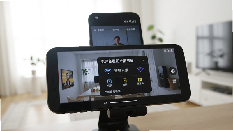 一部手机播放视频时弹出设置菜单,屏幕显示“无码免费影片播放器”字样,旁边有无线网络图标,背景为明亮的室内,手机放在桌面支架上,画质干净,无多余元素。