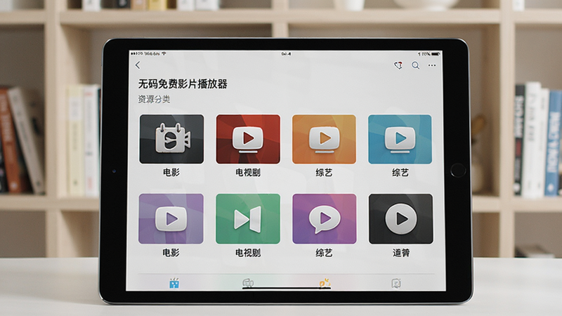 一台平板电脑展示“无码免费影片播放器”的资源分类界面,屏幕上显示电影、电视剧、综艺等分类图标,背景为浅色书架,平板横放,画面明亮,细节丰富,干净整洁。