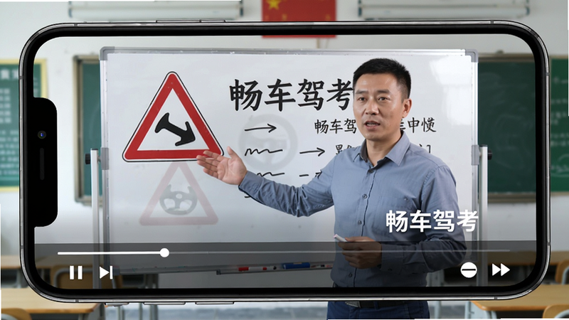 画面主体为畅车驾考App视频播放页面,手机横屏播放,画面中教练正在白板上讲解交通标志,白板上有“畅车驾考”水印,屏幕下方有进度条和播放控制按钮,背景为教室环境,整体布局横屏居中,排版舒适,风格写实,细节包括教练手势和白板文字,画质高清,干净无多余元素