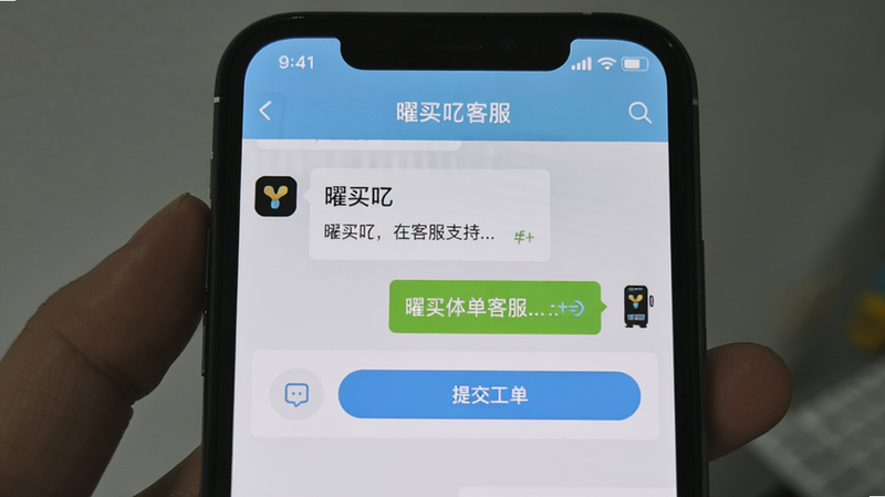 一张展示“曜买吖”客服支持界面的手机截图,屏幕内显示在线客服对话框与“提交工单”按钮,背景为浅蓝色,顶部有“曜买吖客服”字样,整体风格简洁,画质清晰。