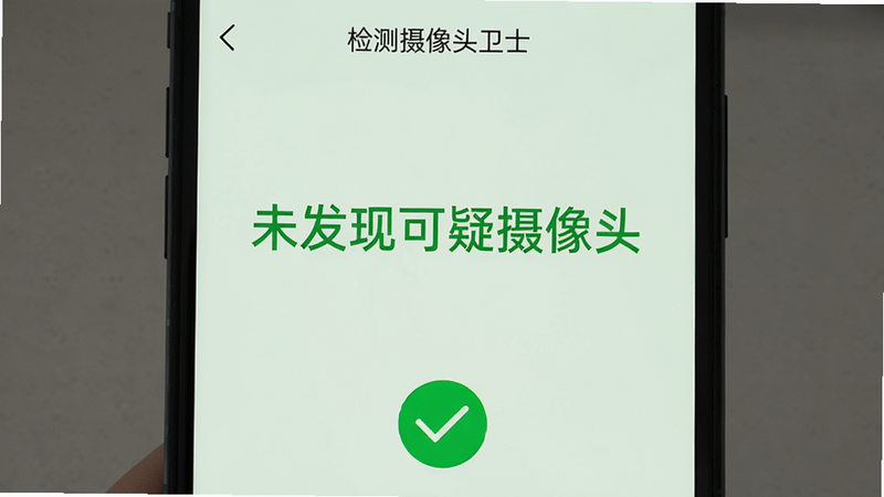 主体为手机屏幕显示“检测摄像头卫士”的检测完成页面,屏幕上显示“未发现可疑摄像头”绿色大字,背景为浅绿色,手机下方有一个对勾图标,整体布局简洁,排版居中,风格清新,细节包括文字、图标、绿色背景,画质干净无多余元素