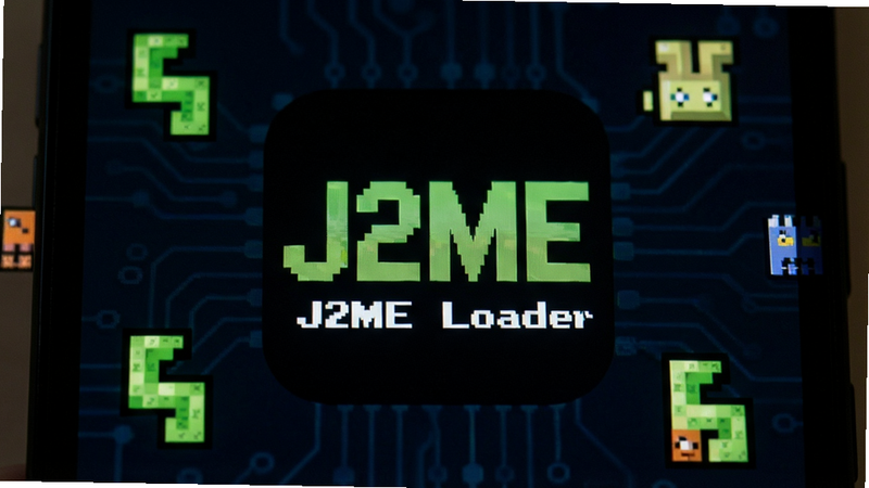 һ��չʾJ2ME LoaderӦ��ͼ���ڰ�׿�ֻ���Ļ�ϵ���дͼƬ������Ϊ��ɫ�����µ���ɫJ2ME Logo�����־��У��Ű��࣬��񸴹ſƼ��磬ϸ�ڰ�����ΧƯ���ľ���J2ME��Ϸ����Ԫ����̰���߷��飬���ʸ��壬�ɾ����޶���Ԫ��