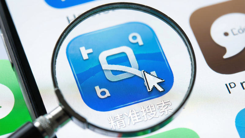 主体为放大镜聚焦于手机应用图标,布局特写式构图,排版突出焦点,风格明亮清晰,细节展示图标光泽与搜索光标,画质细腻,干净无多余元素,文字内容包含
