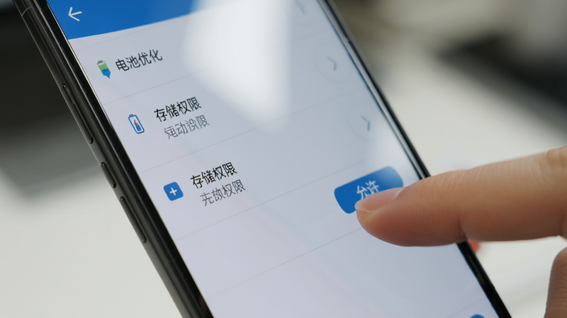 主体为安卓手机设置界面截图,显示“电池优化”和“存储权限”选项,手指正在点击“允许”按钮,背景虚化,风格写实摄影,细节包含手机边框和屏幕反光,画质高清,干净