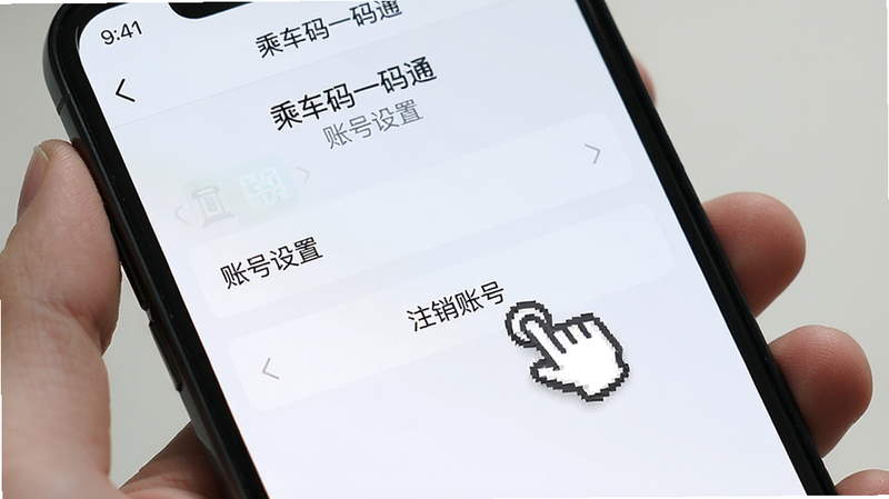 手机屏幕显示“乘车码一码通”APP的“账号设置”页面,列表中包含“注销账号”选项,该选项被手指图标指向,背景为浅色UI设计,文字清晰,风格简洁明了,高清晰度,无其他干扰元素