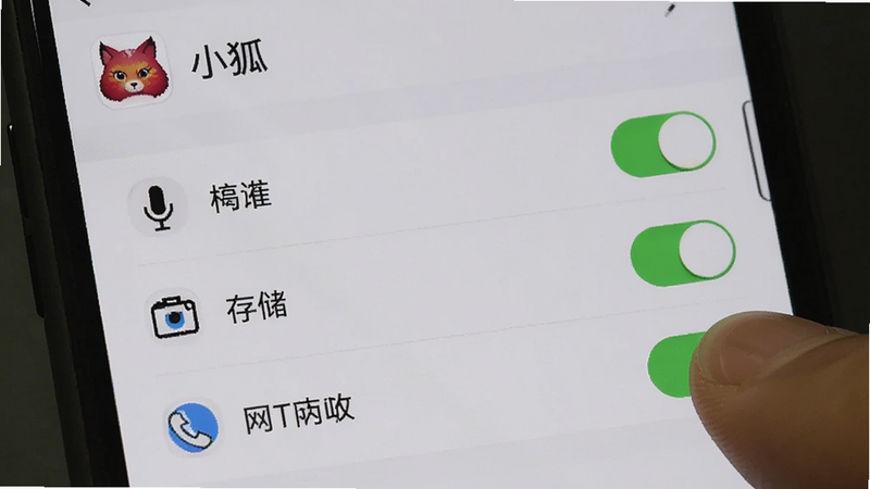 主体为手机设置界面截图,显示“小狐”应用的权限管理页面,包括麦克风、存储、网络等开关,布局清晰,风格系统原生,细节展示手指点击开关的动作,画质清晰,无多余水印