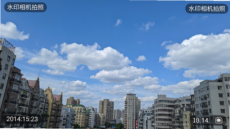 “水印相机拍照”APP拍摄的高清风景样张,主体为蓝天白云下的城市建筑,布局中心突出,风格写实,细节展示照片角落清晰的时间地点水印,画质极佳,干净,无多余元素