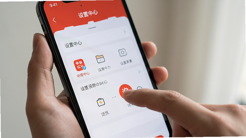 主体为一只手拿着智能手机,屏幕显示中原红APP的设置界面,布局清晰,排版简洁,风格生活化,细节包含手指点击图标动作,画质真实,干净,无多余元素,文字“设置中心”
