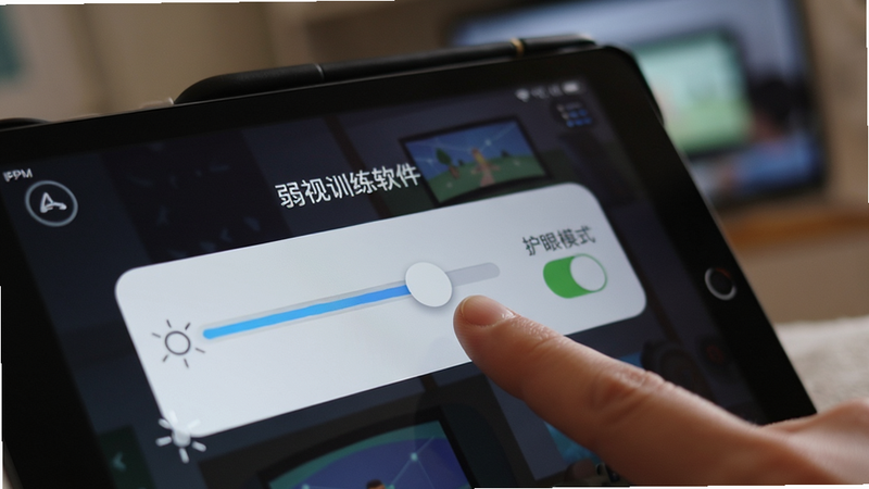 “弱视训练软件”在平板电脑上的设置界面,显示着亮度调节滑块和护眼模式开关,手指正在滑动调节,背景虚化,突出设置功能的细节,高清,清晰