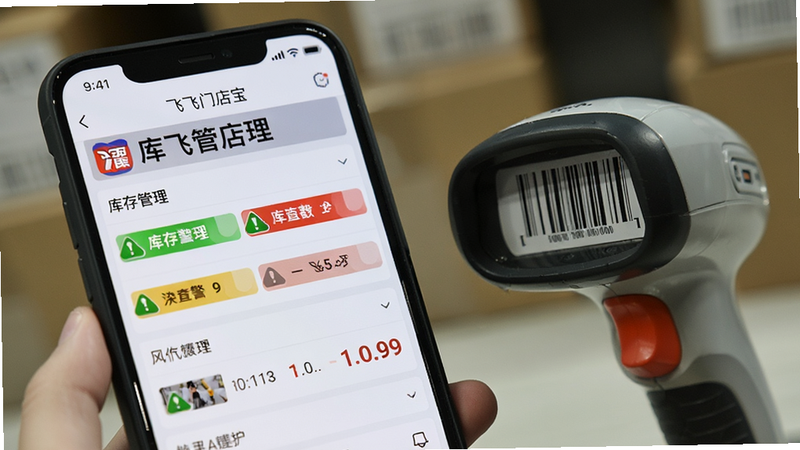 一张特写照片,展示手机屏幕上“飞飞门店宝”的库存管理模块,界面显示绿色和红色的库存预警标识,旁边放着一个条形码扫描枪,背景虚化,突出屏幕清晰度,风格写实,细节清晰,画质高,无水印