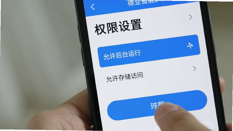 展示手机设置界面中关于德业智能APP的权限管理页面,高亮显示“允许后台运行”和“允许存储访问”选项,界面清晰,手指正在点击确认按钮,风格简洁,色调蓝白,文字“权限设置”醒目