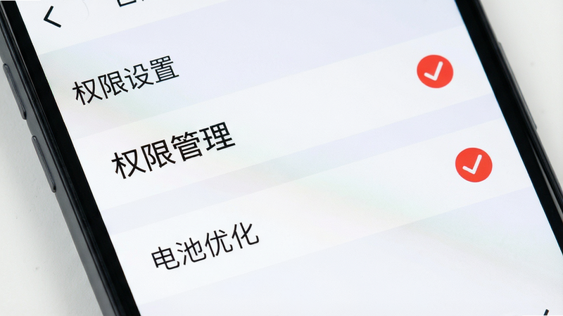 手机设置界面特写,显示“权限管理”和“电池优化”选项被勾选,主体为手机屏幕局部,布局清晰,排版简洁,风格为扁平化UI设计,细节处有红色对勾标记,画质高清,干净,无多余元素,文字“权限设置”清晰
