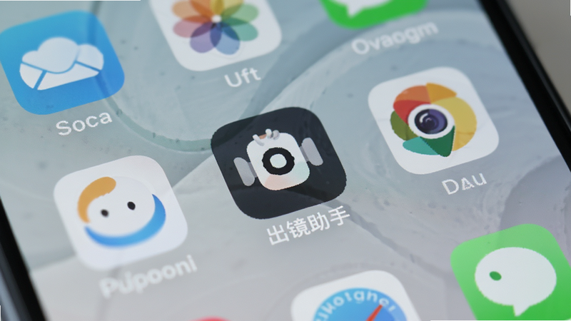 手机主屏幕界面,显示“出镜助手”APP图标位于显眼位置,周围有其他常用应用图标,背景为柔和的壁纸,体现日常使用的便捷性,画面干净,无多余元素