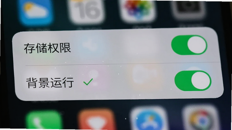 手机设置界面特写,显示“存储权限”和“背景运行”开关已开启,旁边有一个绿色的对勾图标,背景为模糊的手机桌面,界面简洁,重点突出权限设置项