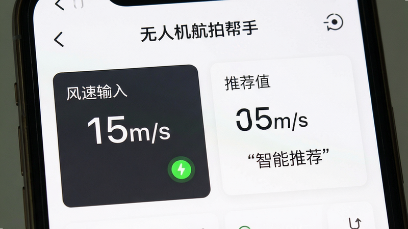 主体为手机屏幕显示“无人机航拍帮手”的飞行参数计算界面,布局分为风速输入区与推荐值输出区,排版左右分栏,风格为极简白色背景配深灰文字,细节显示数字“15m/s”与绿色安全指示灯,画质清晰,干净,无多余装饰,文字加引号“智能推荐”