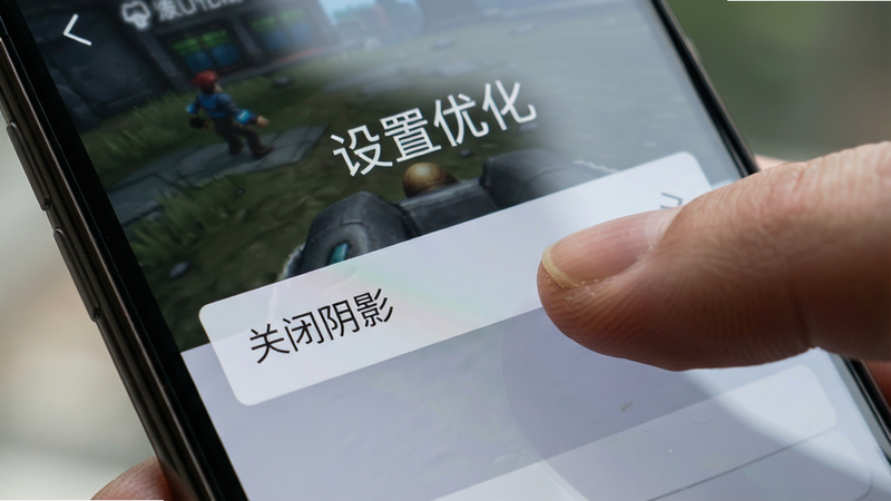 主体为手机屏幕特写,显示游戏设置界面,布局清晰,手指正在点击“关闭阴影”选项,排版简洁,风格写实,细节显示屏幕反光与手指纹理,画质高清,干净,无多余图标,文字“设置优化”悬浮显示