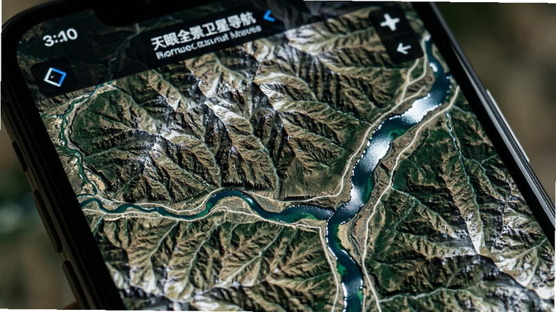 特写手机屏幕上的卫星地图细节,主体为“天眼全景卫星导航”显示的高清地形图,布局聚焦于山脉与河流交汇区域,风格写实自然,细节呈现岩石质感与水体反光,画质极清晰,无UI干扰,突出地图纹理的真实感