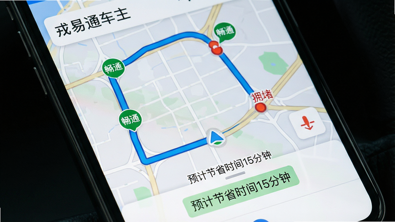 手机屏幕特写,显示“戎易通车主”App内的地图导航界面,地图上有一条醒目的蓝色路线,沿途标注着绿色的畅通节点和红色的拥堵节点,界面下方有“预计节省时间15分钟”的提示标签,背景为淡灰色网格地图,布局紧凑,风格扁平化,细节清晰,画质高清,干净,文字