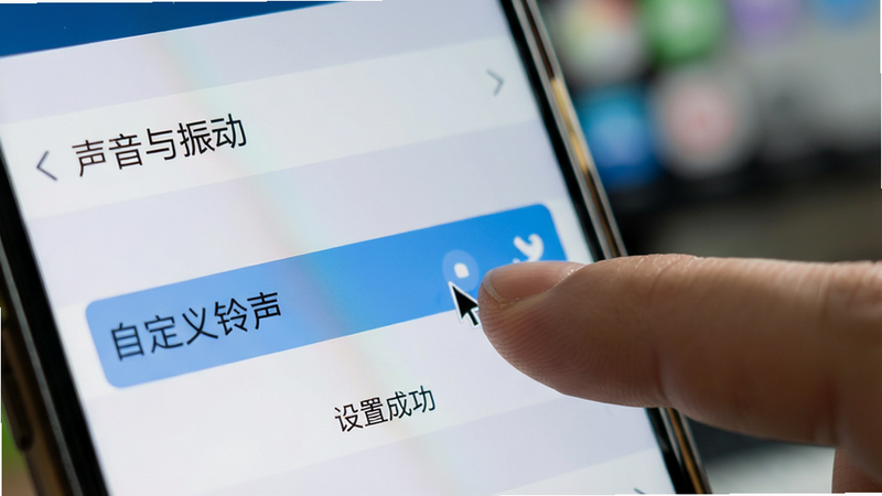 主体为手机设置界面特写,显示“声音与振动”选项,手指点击“自定义铃声”,背景虚化,布局聚焦,写实风格,细节处有光标和选中高亮,画质清晰,干净无干扰元素,文字包含“铃声精选免费”和“设置成功”