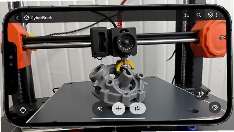 手机屏幕显示CyberBrick应用内的实时摄像头监控画面,画面清晰展示3D打印机喷嘴正在打印一个复杂的机械零件,界面下方有简单的控制按钮,风格写实,高清