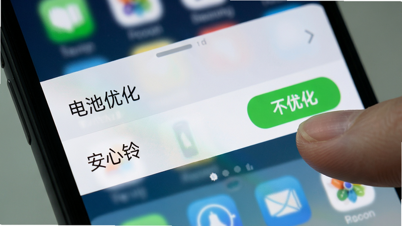 手机设置界面的特写,显示“电池优化”选项列表,其中“安心铃”被高亮选中,旁边有一个绿色的“不优化”按钮,手指正点击该按钮,背景为模糊的手机桌面,风格写实,细节清晰,画质高,干净无杂乱元素,文字“安心铃”清晰可见