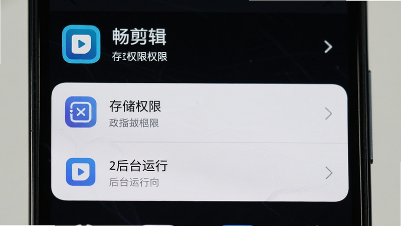 手机设置界面特写,显示“畅剪辑”应用存储权限和后台运行选项,界面清晰,文字可辨,风格扁平简洁,布局垂直排列,细节准确,画质高清,无多余图标