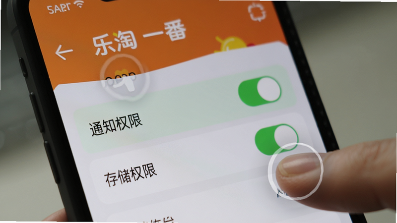 主体为手机屏幕特写,显示乐淘一番APP的设置页面,高亮显示“通知权限”和“存储权限”开关为开启状态。布局简洁,背景虚化,风格扁平化UI设计,细节处有手指点击的动效示意,画质清晰,光线均匀,无多余图标干扰,突出操作重点。